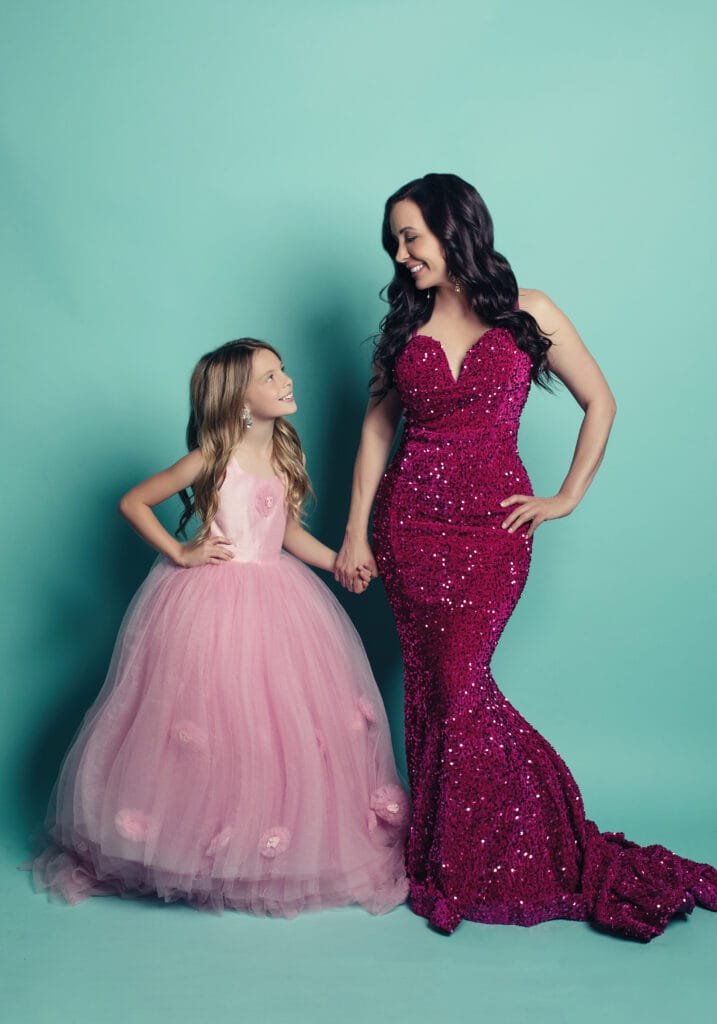 MyBioGlow founder with daughter in formal gowns, celebrating beauty and confidence.