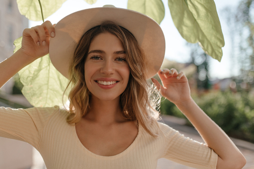 Young,Woman,Smiling,With,Teeth,In,Stylish,Hat,,Hiding,From